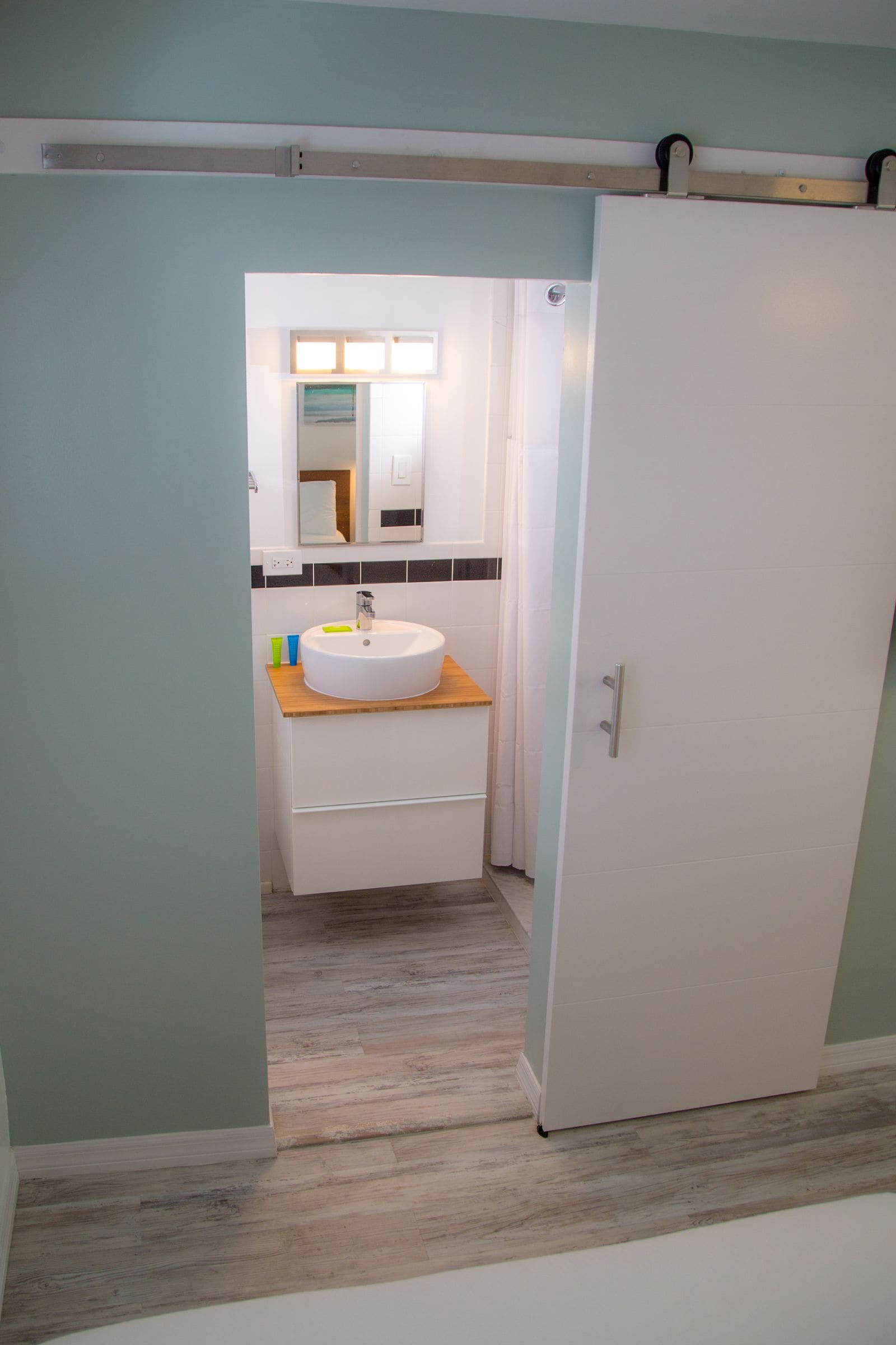 Un baño con lavamanos blanco, encimera de madera y espejo arriba.