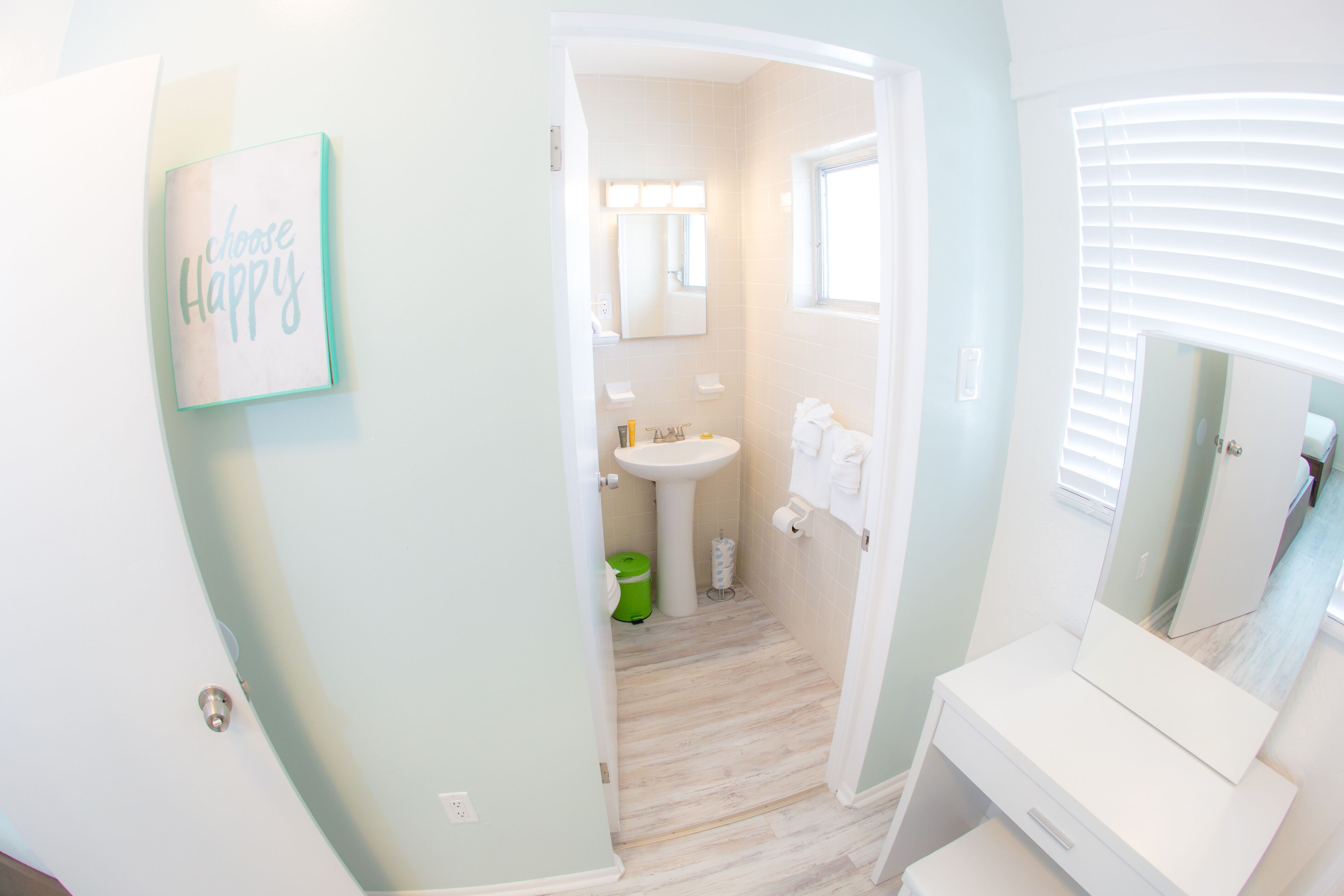 A bathroom with a sink, mirror, and a 'choose happy' sign.