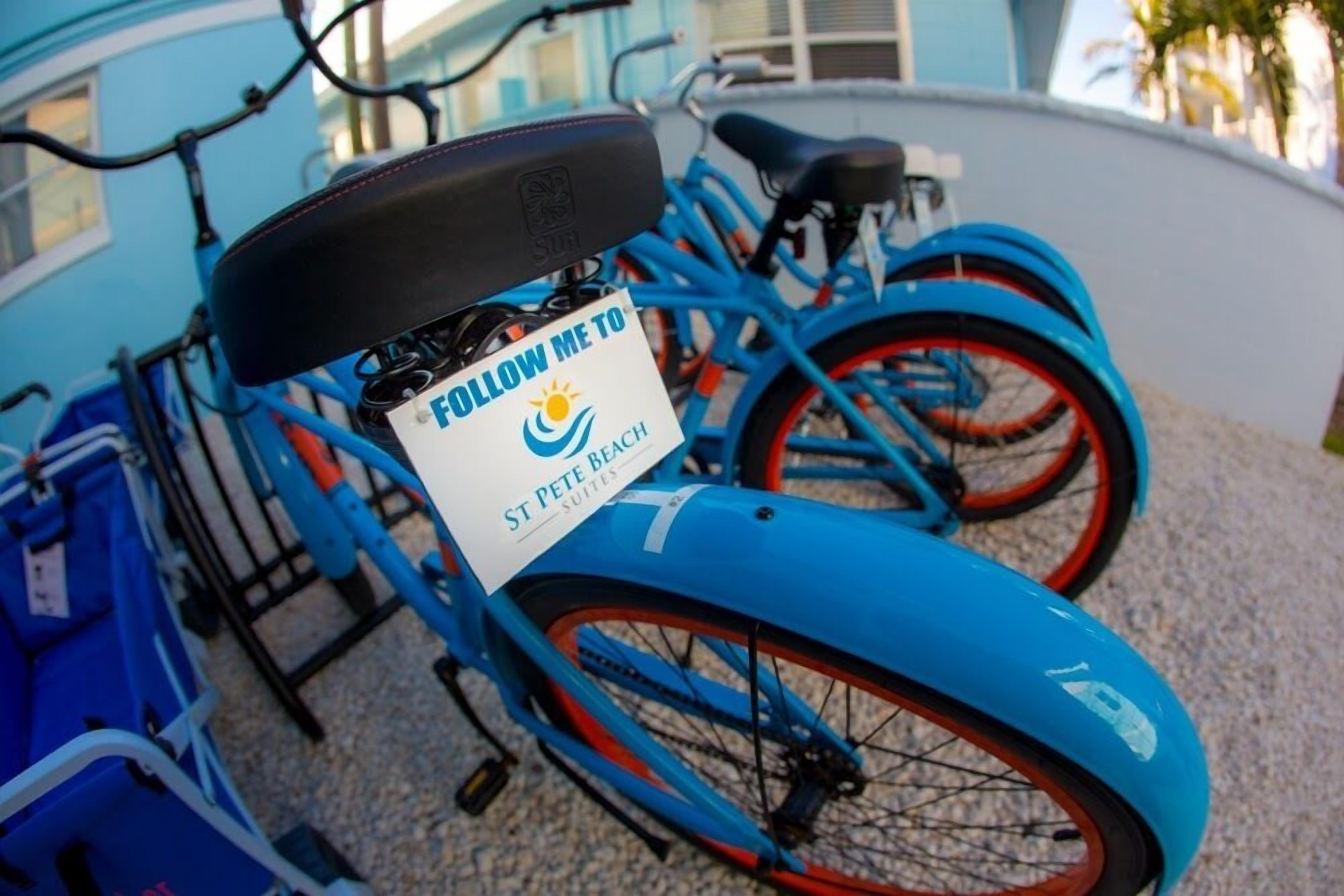 A blue bicycle with a 'Follow Me To St Pete Beach Suites' sign attached to the seat.