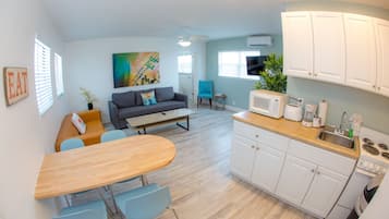A modern kitchen with white cabinets, a wooden countertop, and a dining area with a table and chairs.