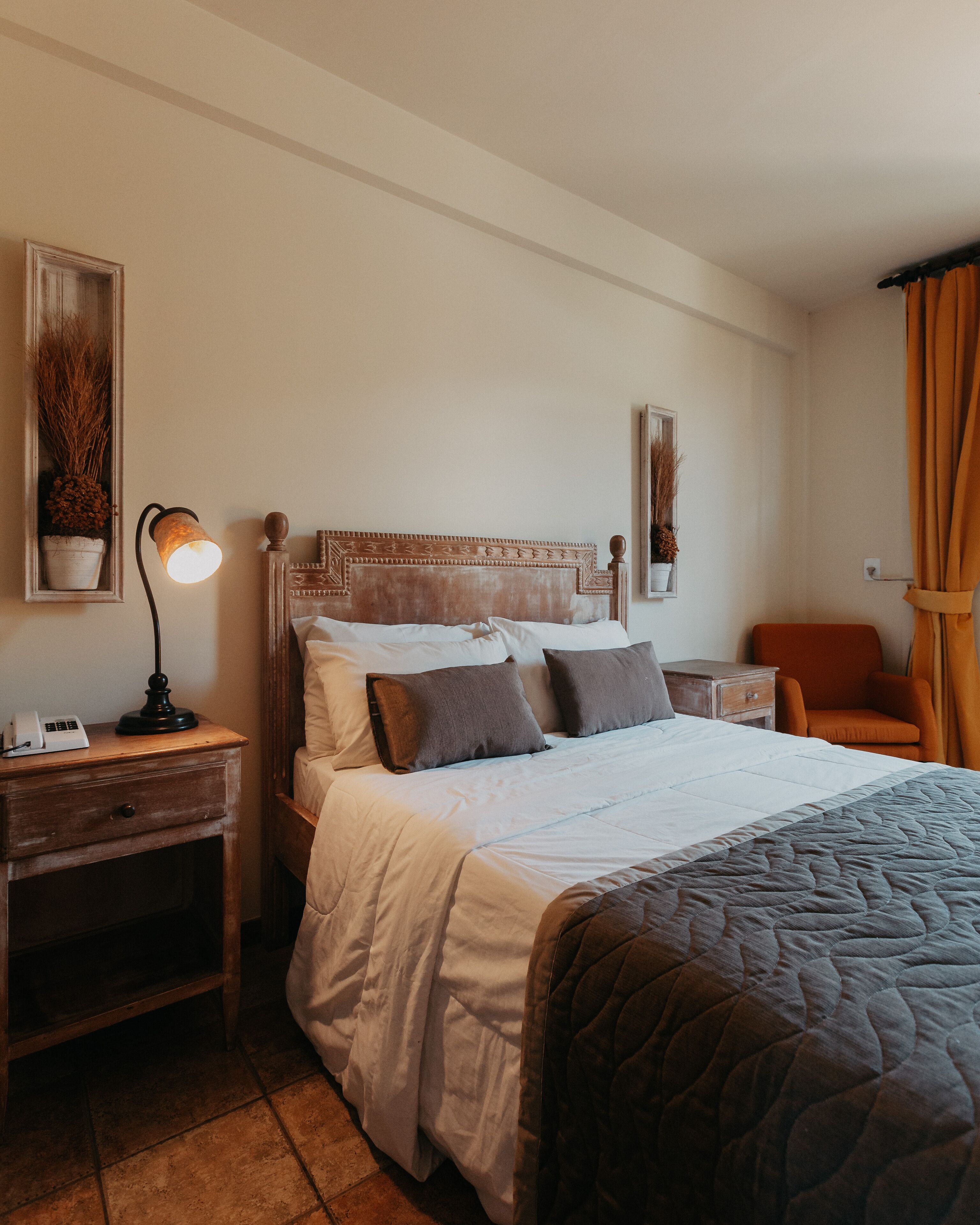 A neatly made bed with pillows, a bedside lamp, and a nightstand with a phone.