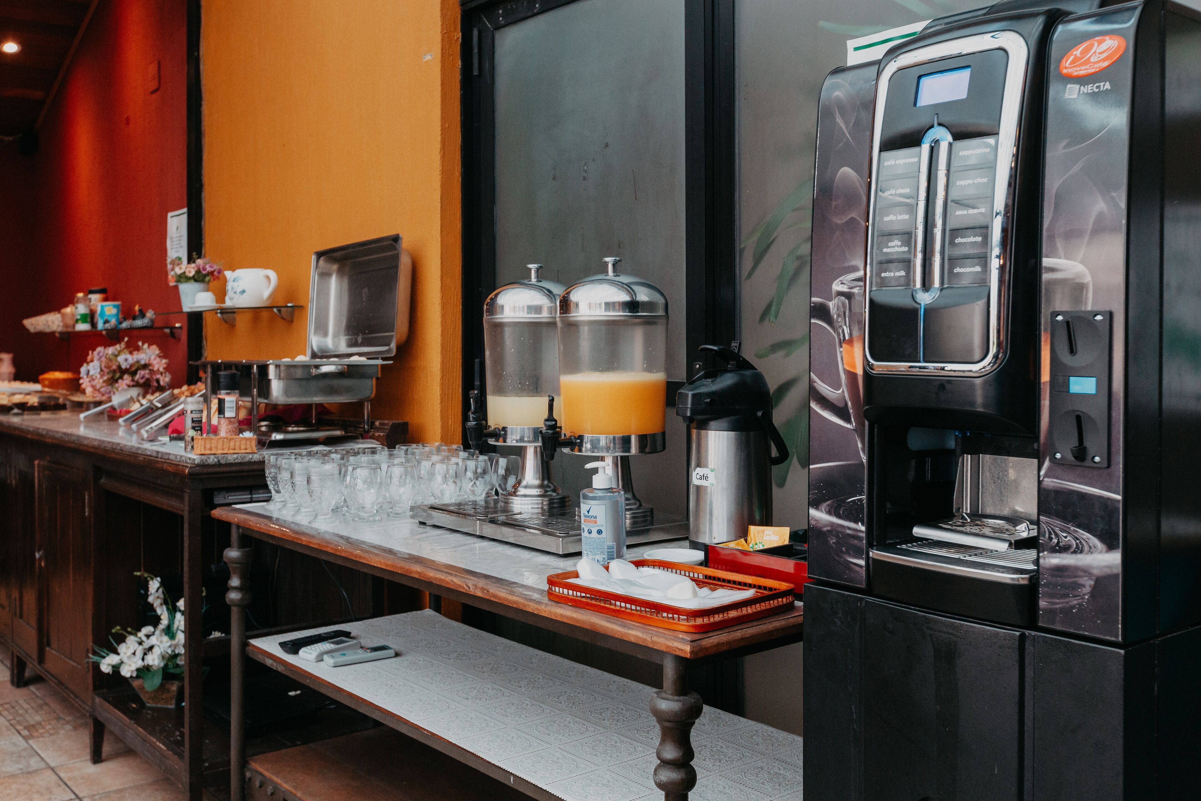 A coffee station with a coffee machine, milk frother, and two milk dispensers.
