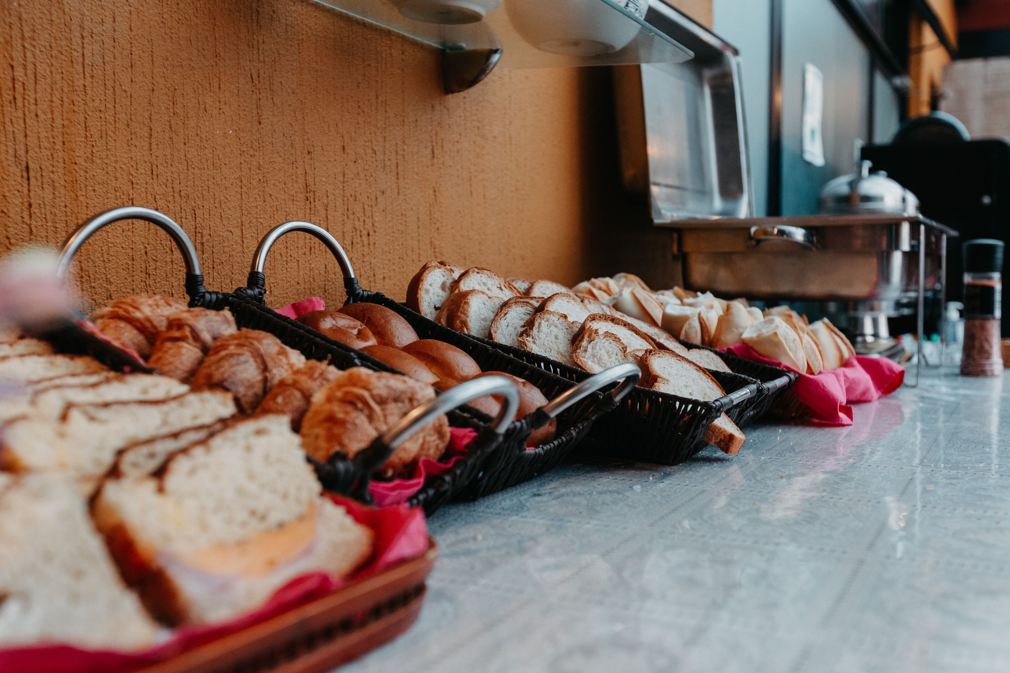 A buffet table with various bread and pastries.