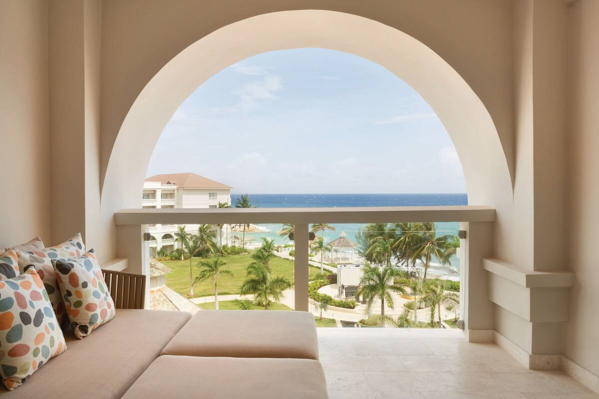 A balcony with a view of the ocean and resort buildings.