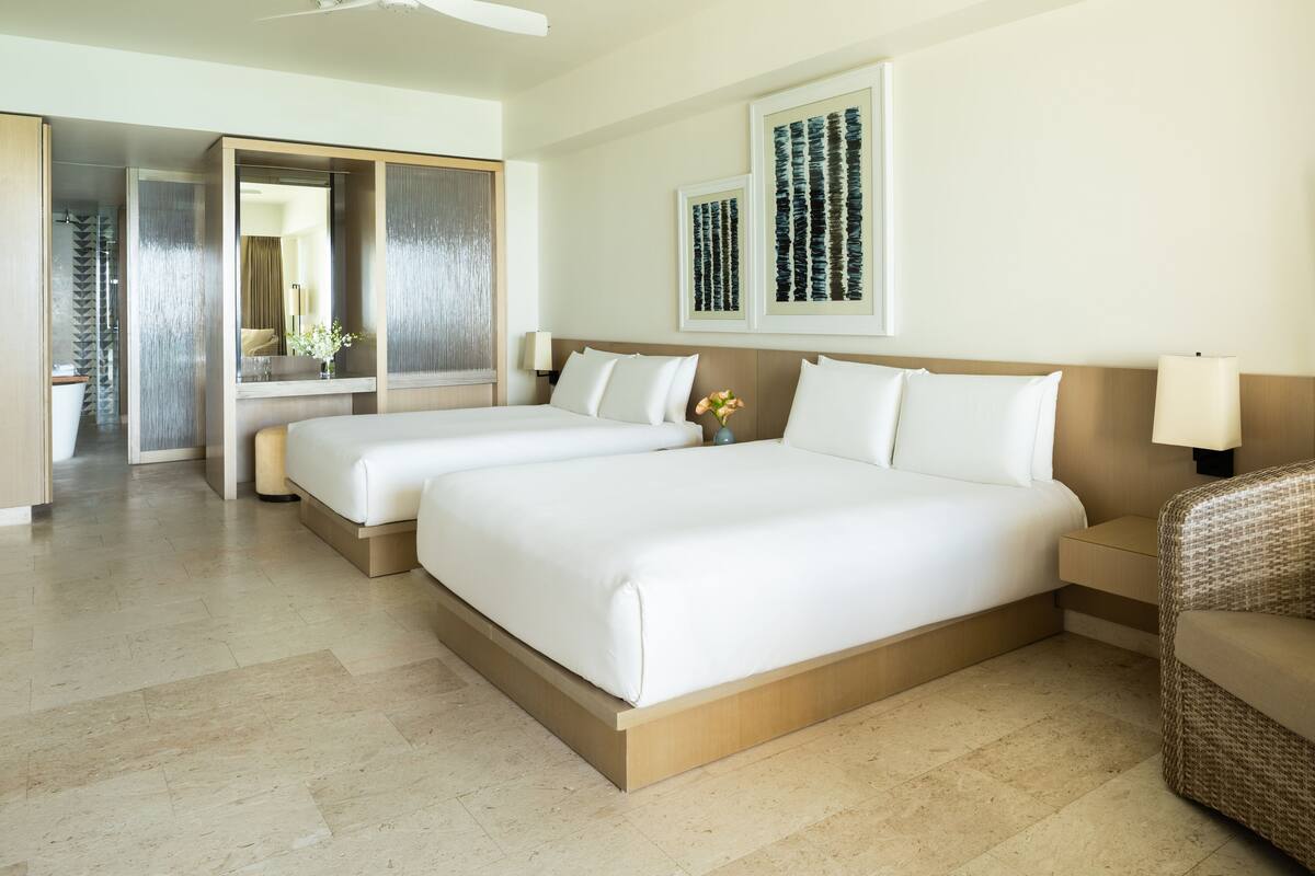A hotel room with two beds, a large mirror, and artwork on the wall.