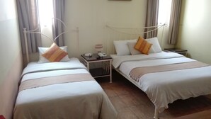 Habitació d'hotel amb dos llits individuals, una taula de nit amb una làmpada i un telèfon, i una taula petita amb un telèfon.