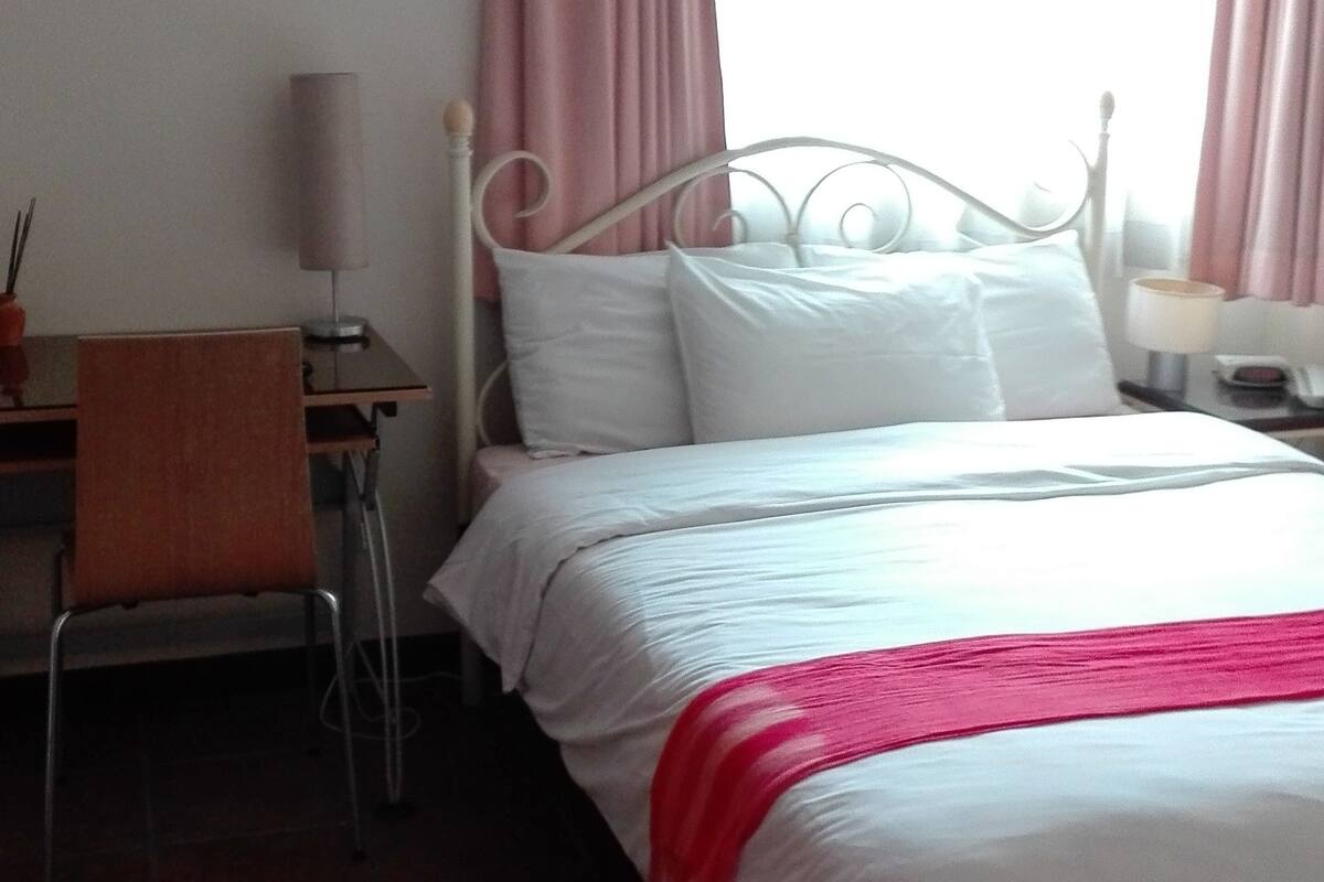 A neatly arranged bedroom with a bed, a desk, and a chair.