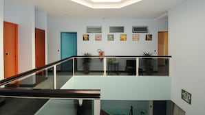 Un interior modern amb barana de vidre, un fanal i una escala.