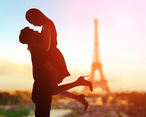 A silhouette of a couple embracing with the Eiffel Tower in the background.