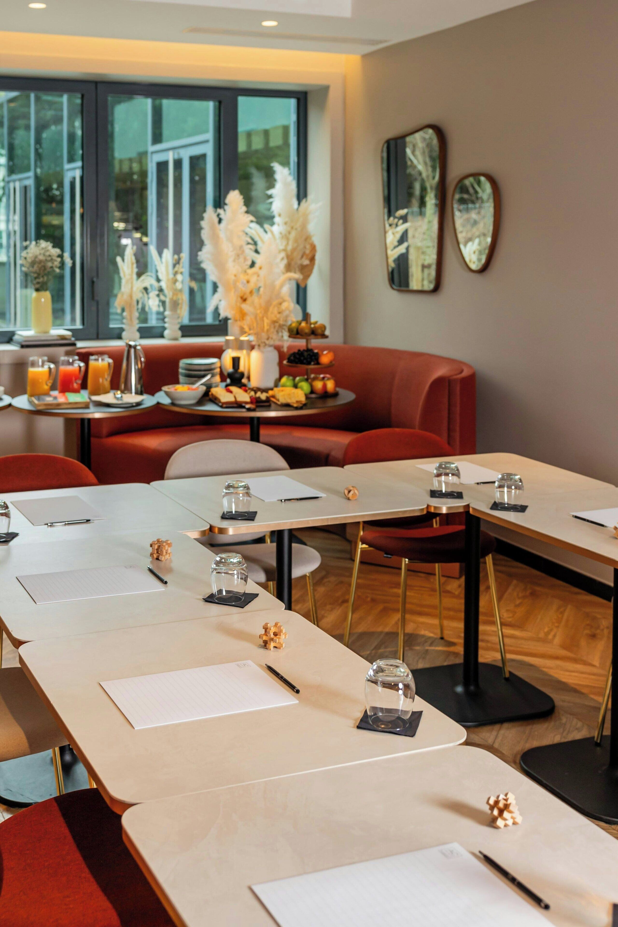 A conference room with long tables, chairs, and a buffet table with food and drinks.
