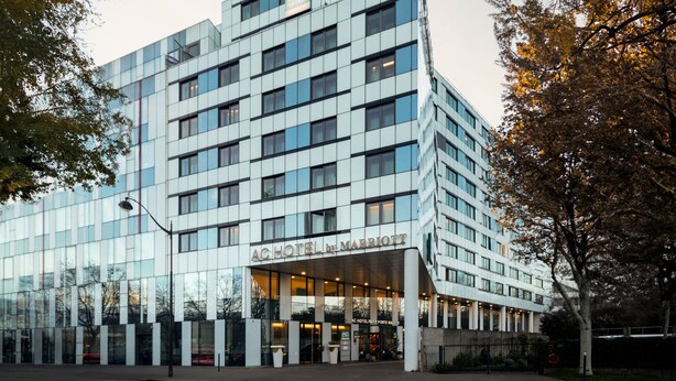 Un hôtel moderne doté d’une façade en verre, d’une entrée imposante et d’une enseigne indiquant qu’il s’agit d’un hôtel Marriott.