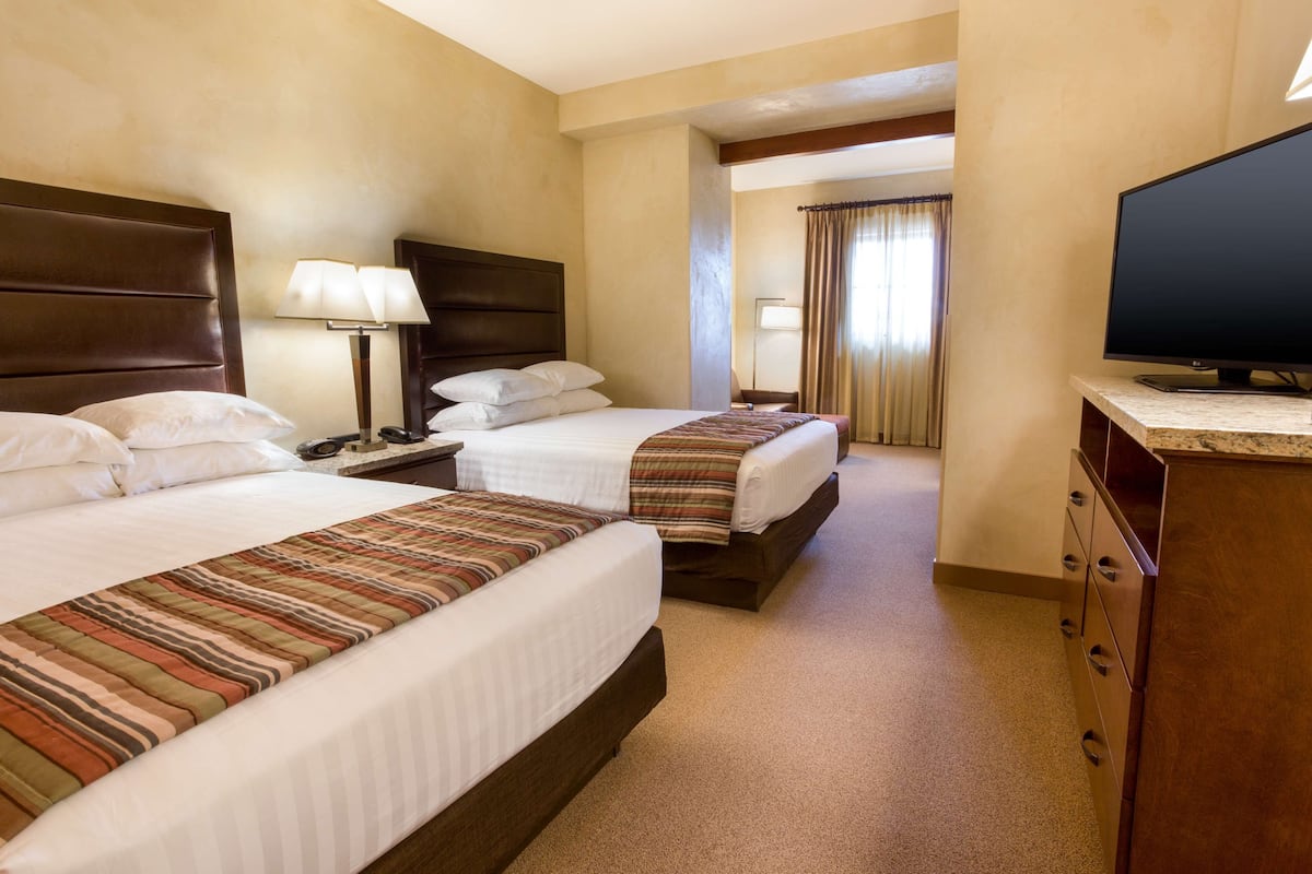 Une chambre d’hôtel avec deux lits, une télévision, un bureau et une lampe.