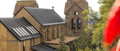 A church with a prominent bell tower and a steeple, surrounded by trees.