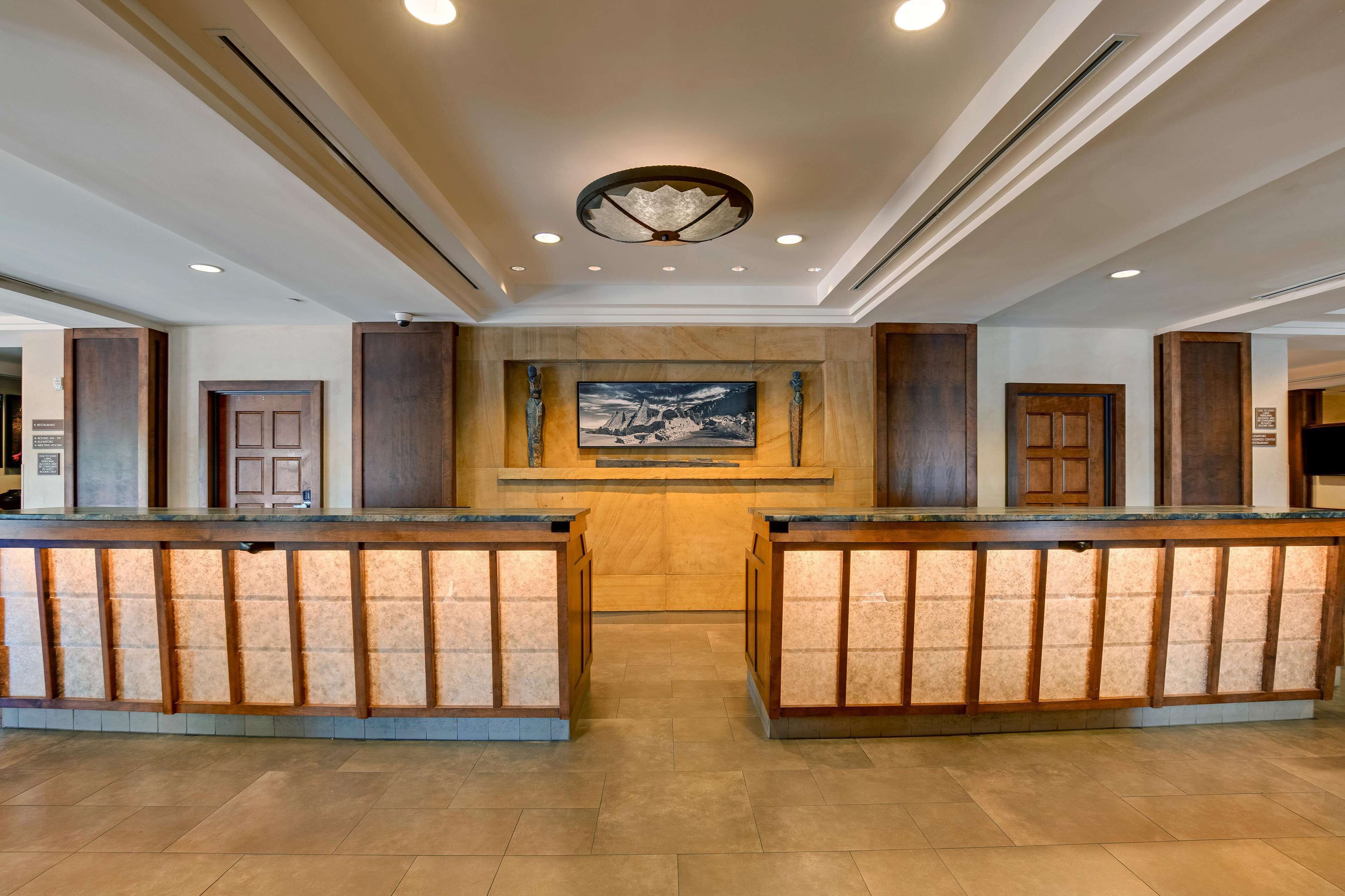 A reception area with a central desk, a large painting on the wall, and wooden paneling.