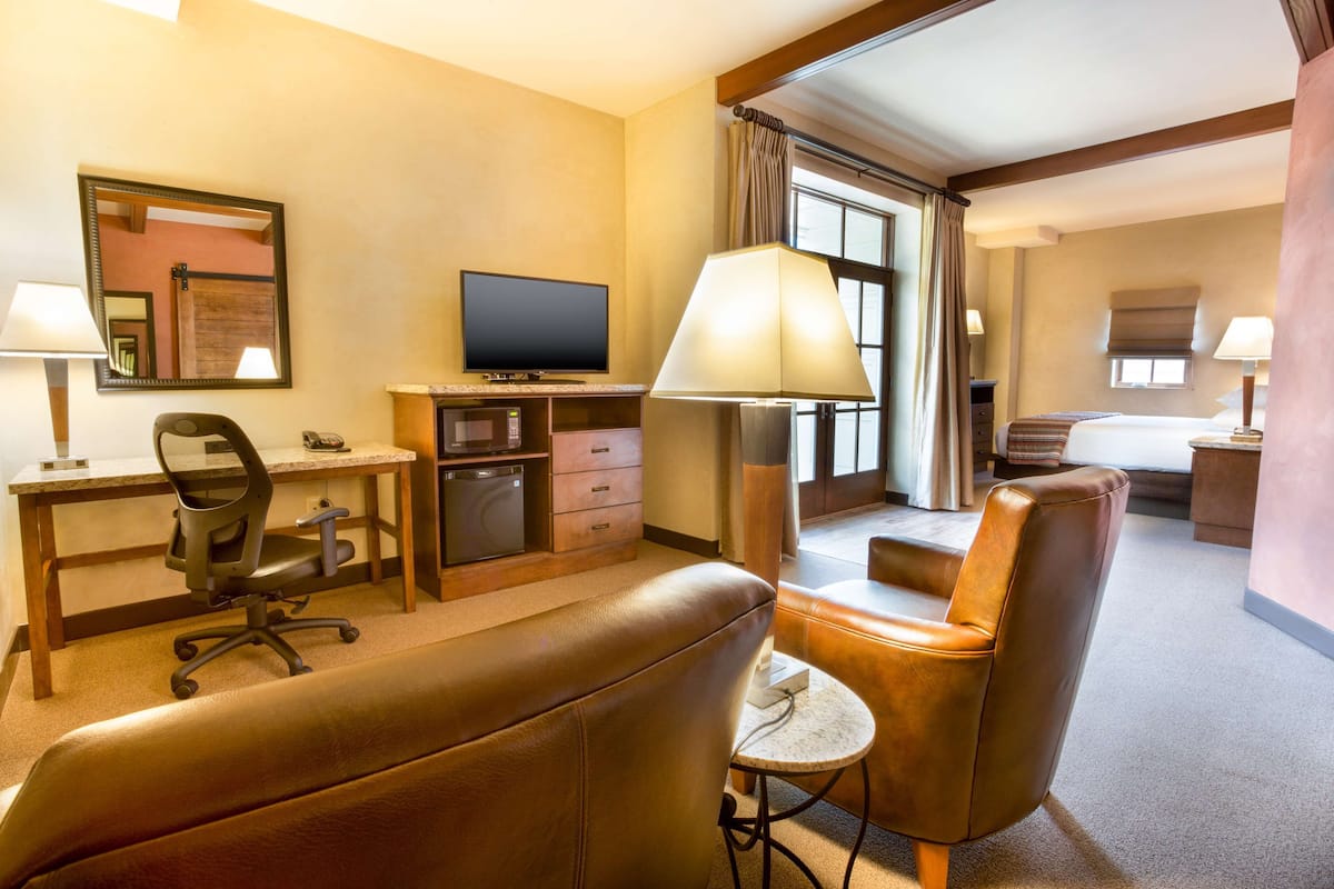 Une chambre d’hôtel équipée d’un bureau, d’une chaise, d’une télévision, d’un canapé et d’une petite table.