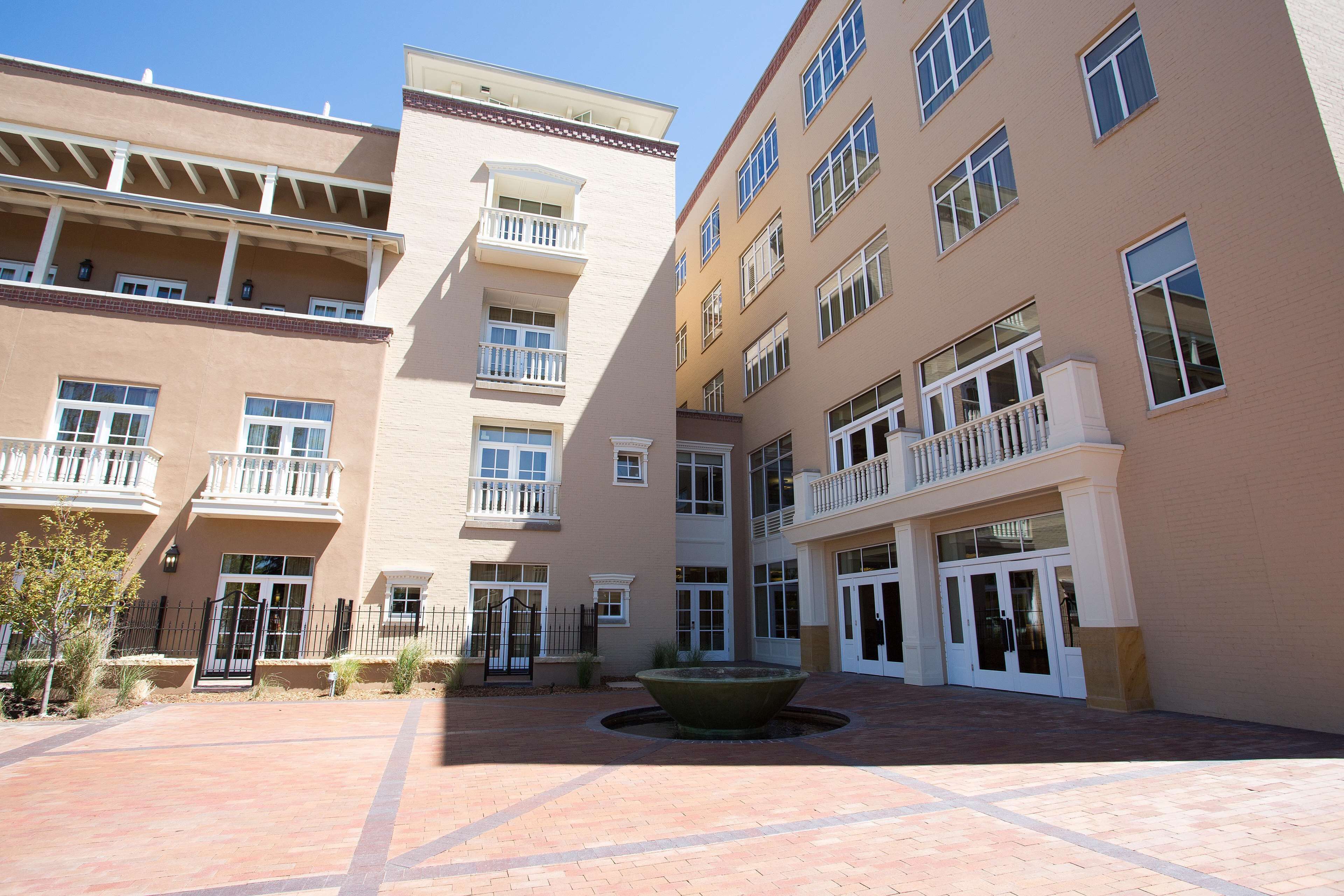 Un patio central con una fuente, rodeado de edificios de varios pisos con balcones y ventanas amplias.