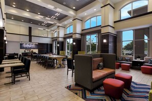 A spacious hotel lobby with a large seating area, a bar, and a television screen. - Hampton Inn & Suites Wilmington Christiana (Newark)