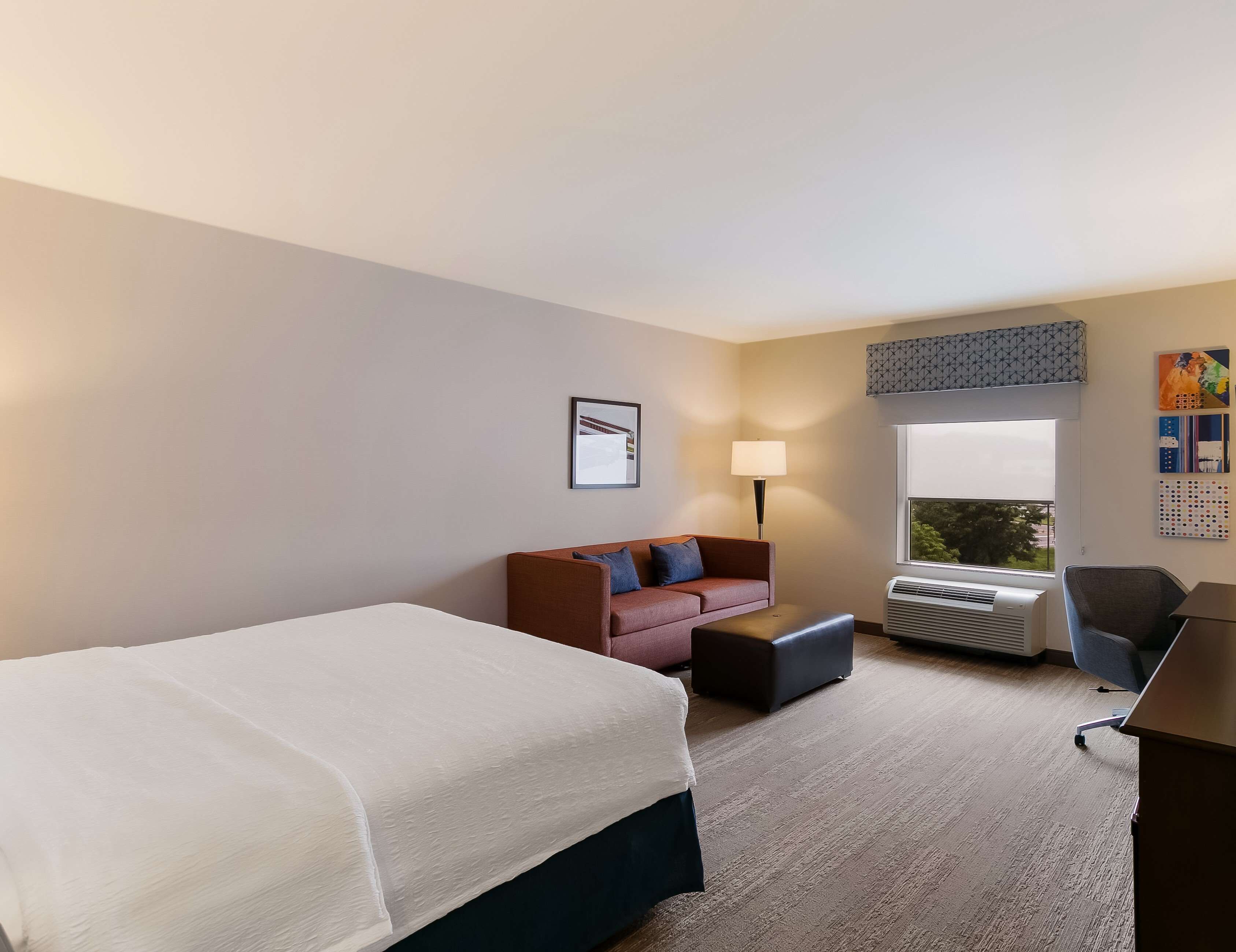 A hotel room with a large bed, a sofa, a desk, and a window with a view.