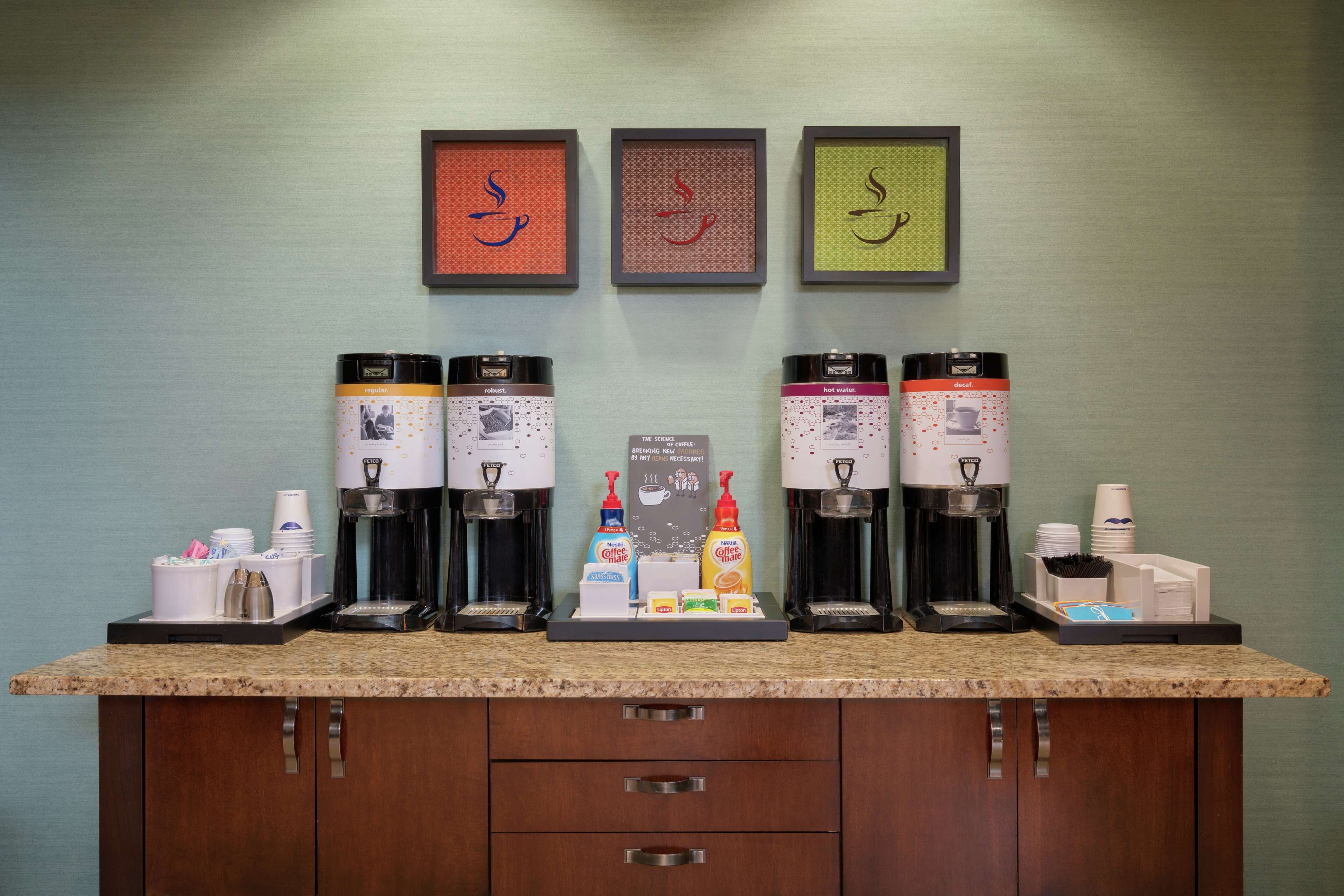 A coffee station with multiple coffee makers and a variety of coffee pods.