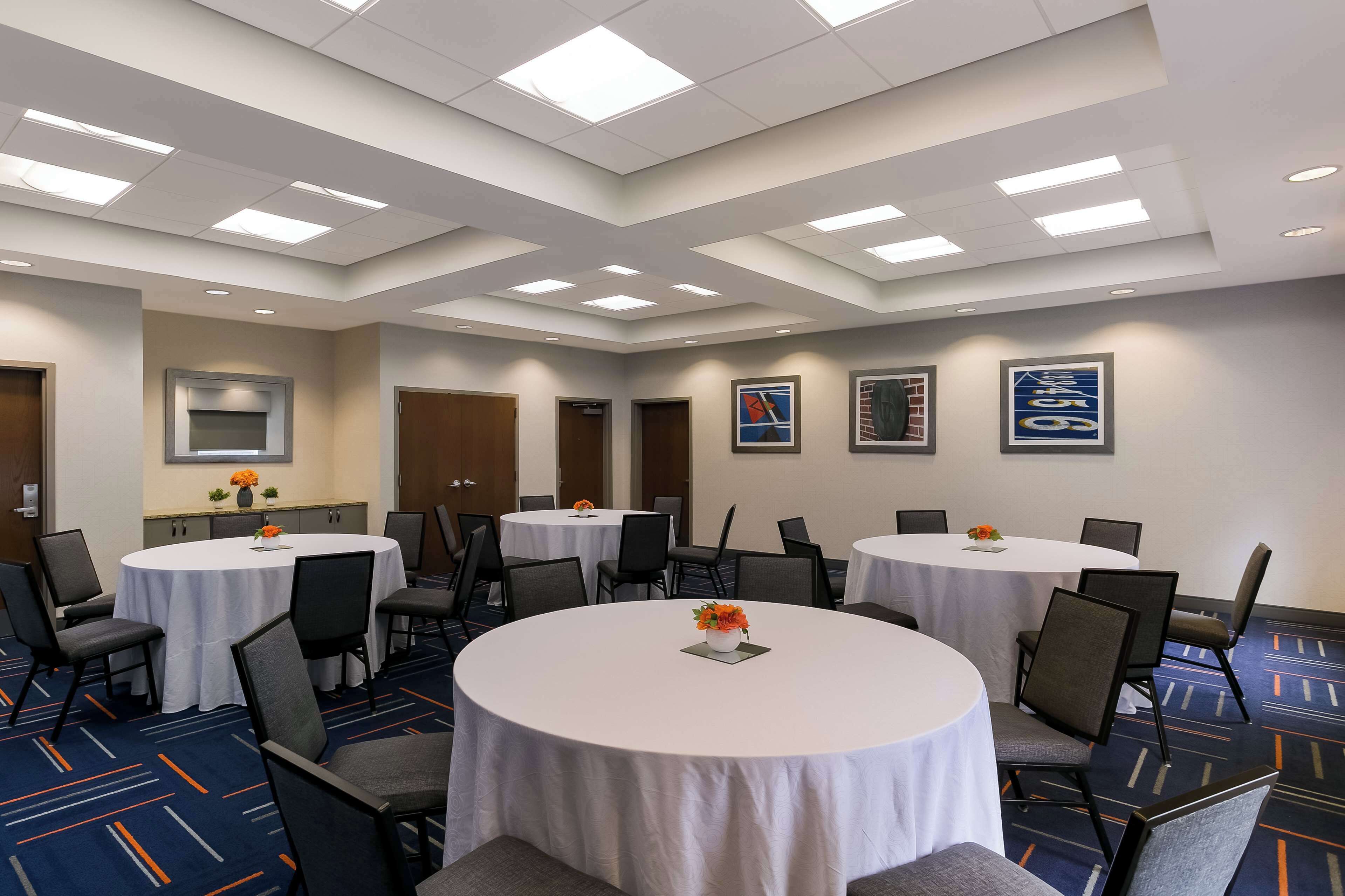 A conference room with round tables, chairs, and a carpeted floor.