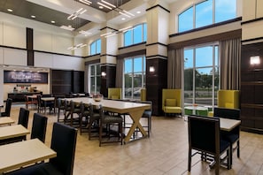 Un restaurante espacioso con techos altos, ventanas amplias e iluminación moderna.