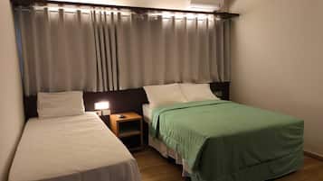 Habitación de hotel con dos camas, una mesita de noche con lámpara y un equipo de aire acondicionado sobre las camas.
