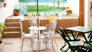 Un patio con una mesa y sillas, un paraguas amarillo y un mural de una playa.