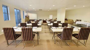 A conference room with multiple tables and chairs, a whiteboard, and a projector screen.