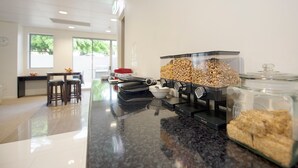 A coffee station with a coffee machine, bowls, and containers of coffee beans. - Gladstone City Central Apartment Hotel (Gladstone)
