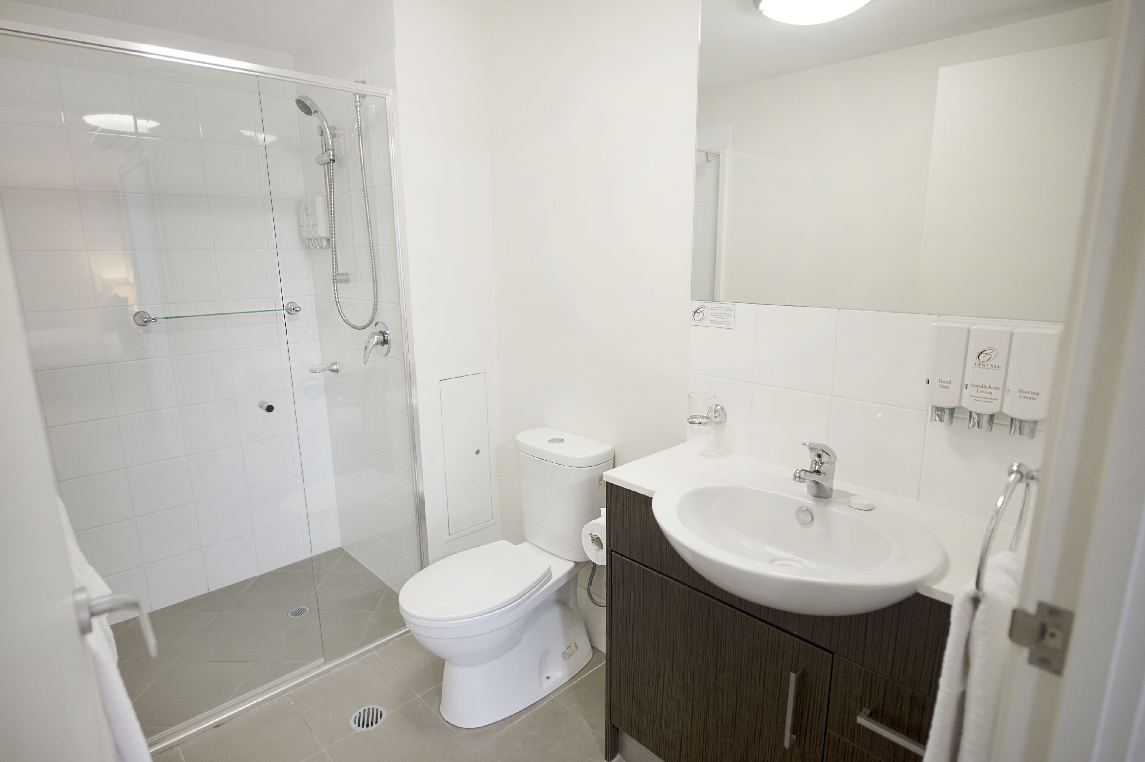 A modern bathroom with a glass shower enclosure, a white toilet, and a vanity with a sink and mirror.