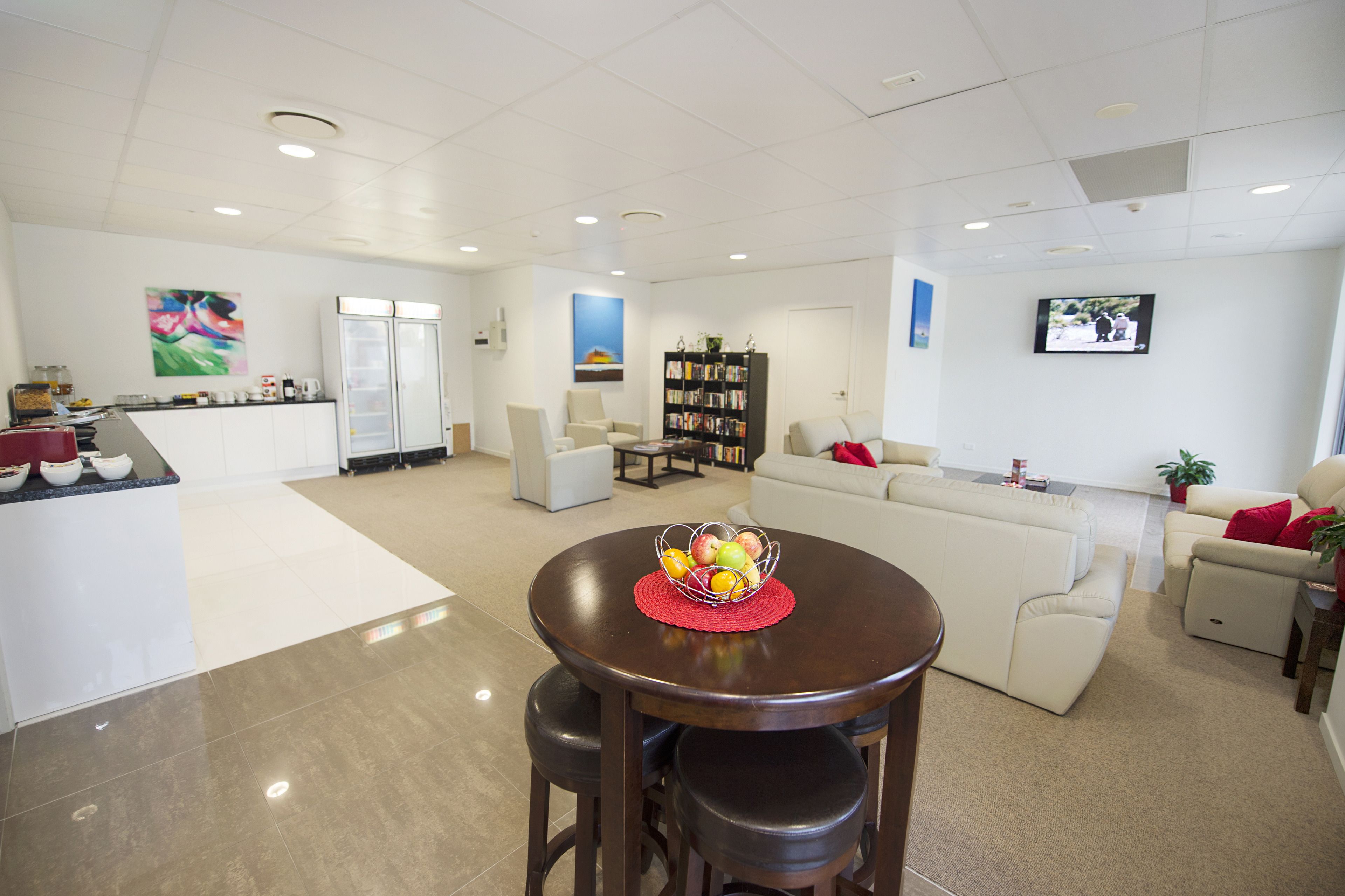 Un salón amplio con una mesa redonda de madera, un sofá blanco y una estantería.