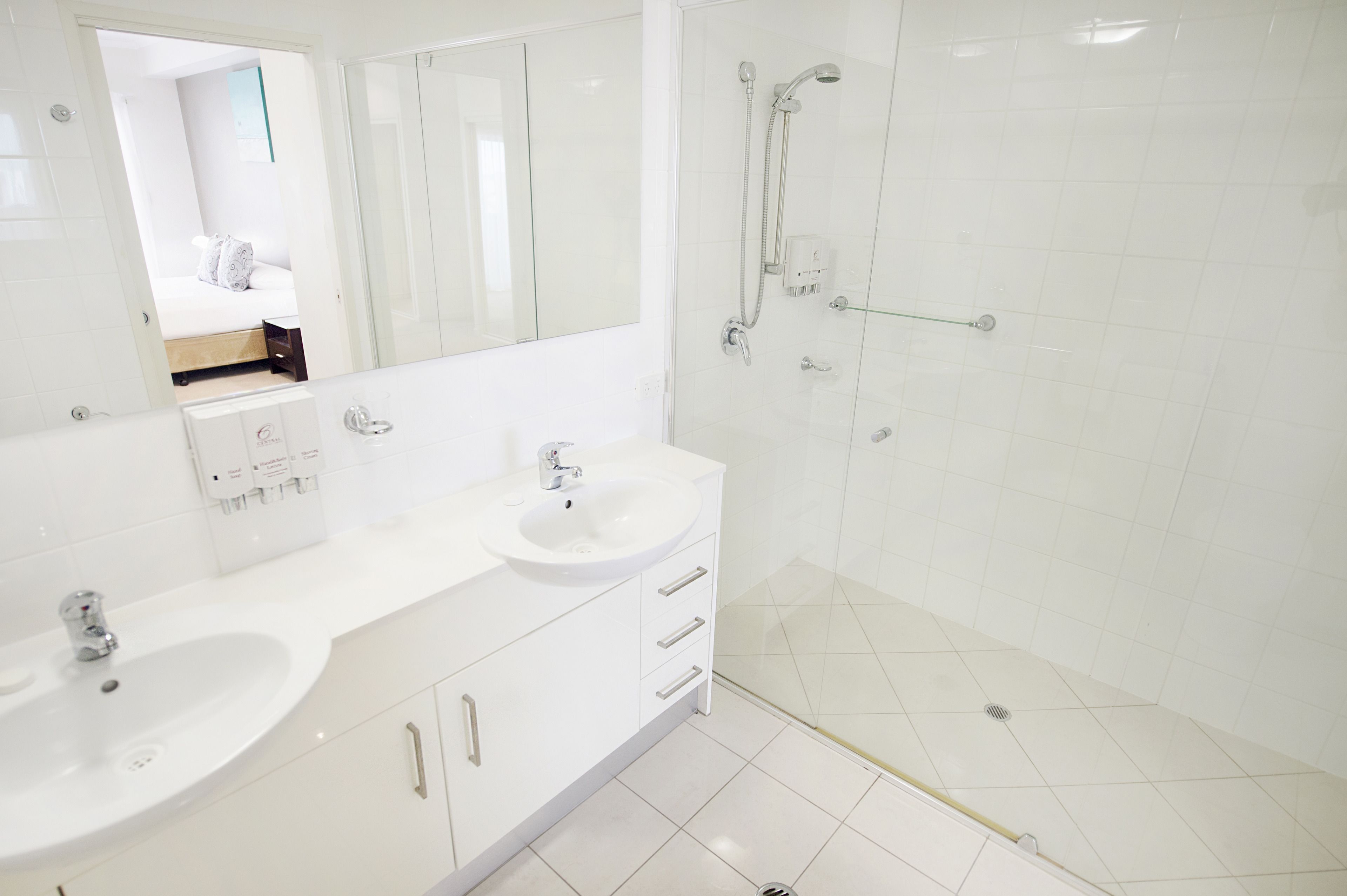 Un bagno moderno con due lavabi, uno specchio grande e una cabina doccia in vetro.