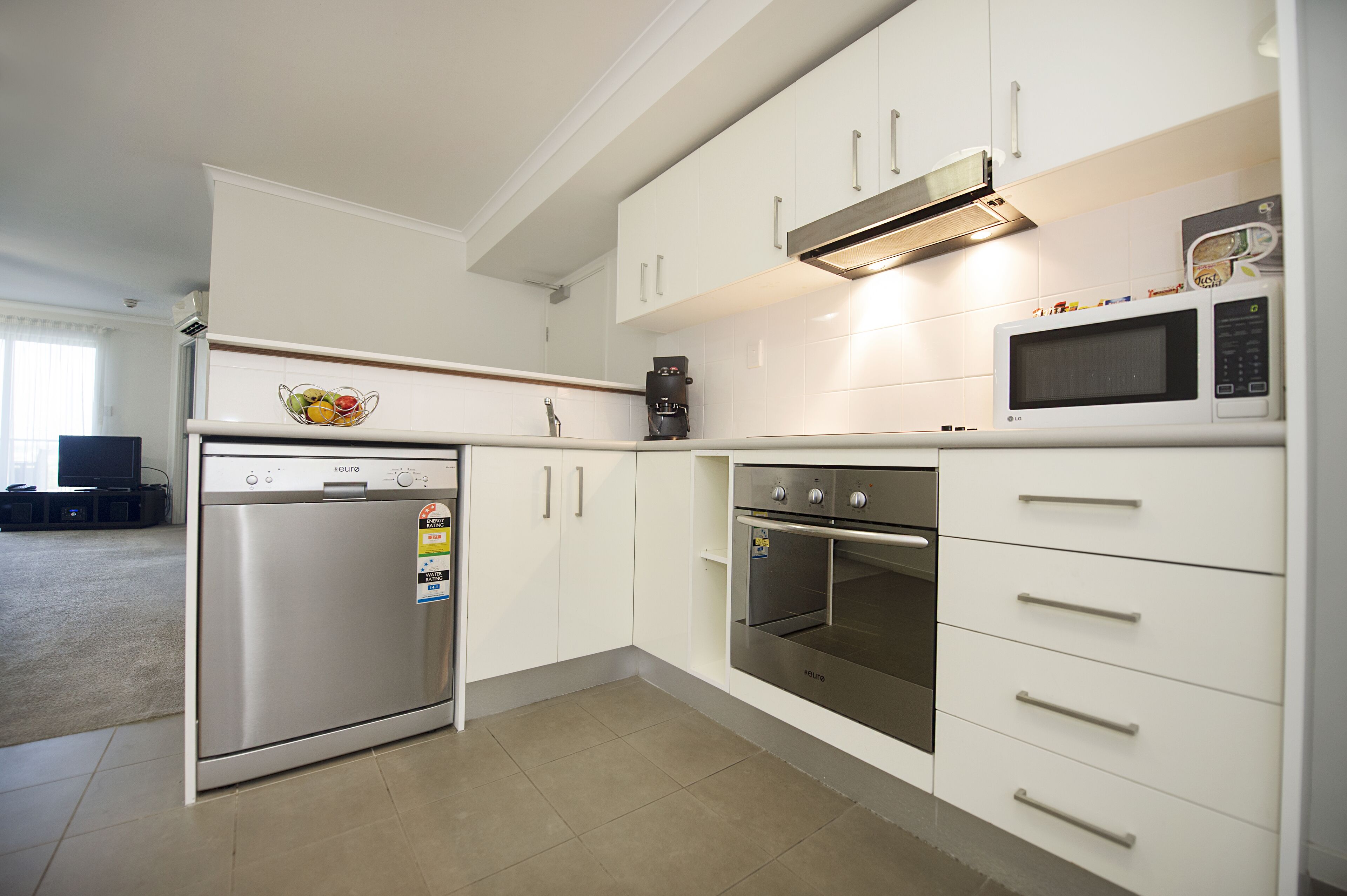 A modern kitchen with white cabinets, stainless steel appliances, and a built-in oven.