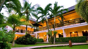 Un hotel a più piani con un cortile centrale, palme e facciata ben illuminata.