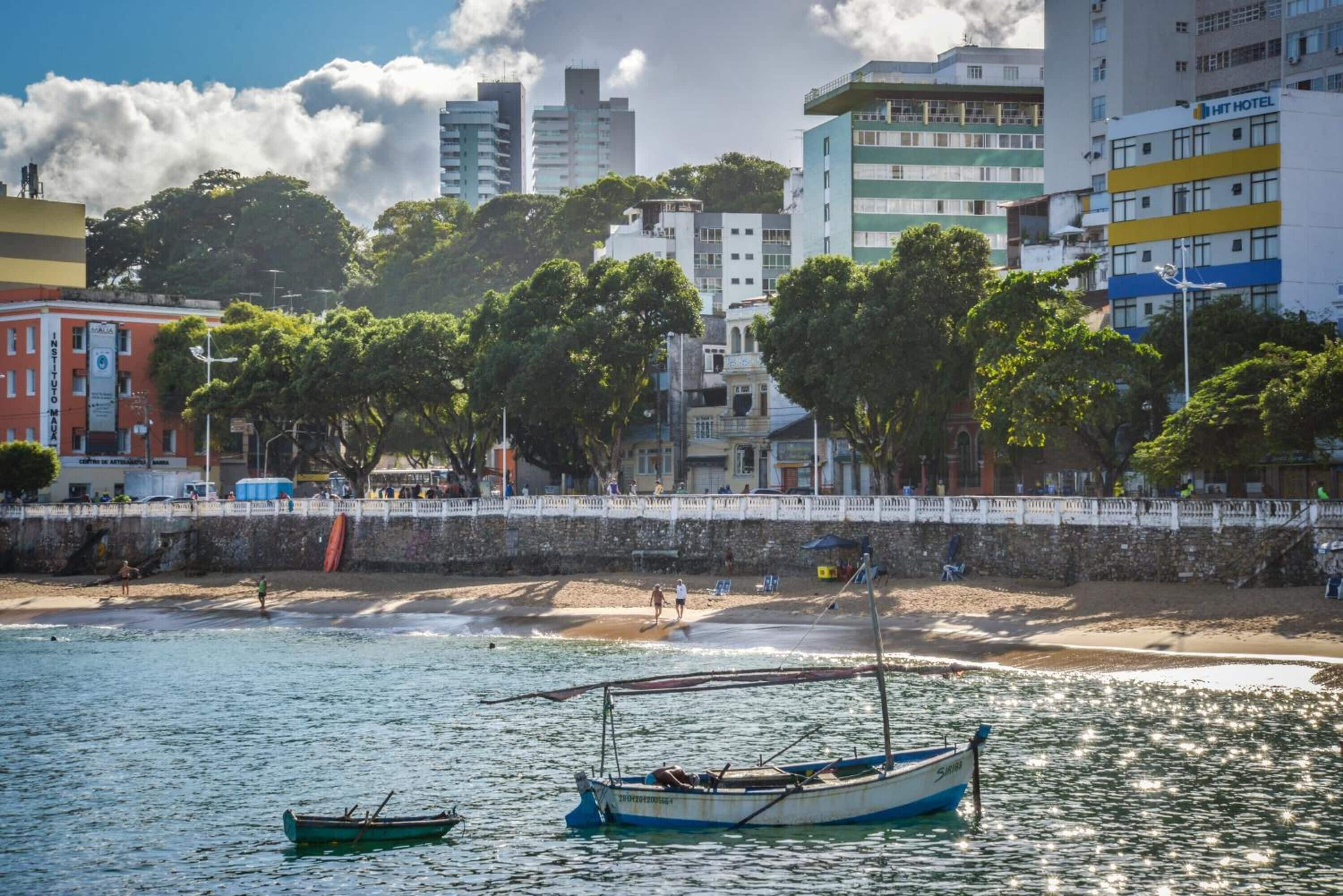 Un paisaje urbano costero con playa, barcos y edificios.