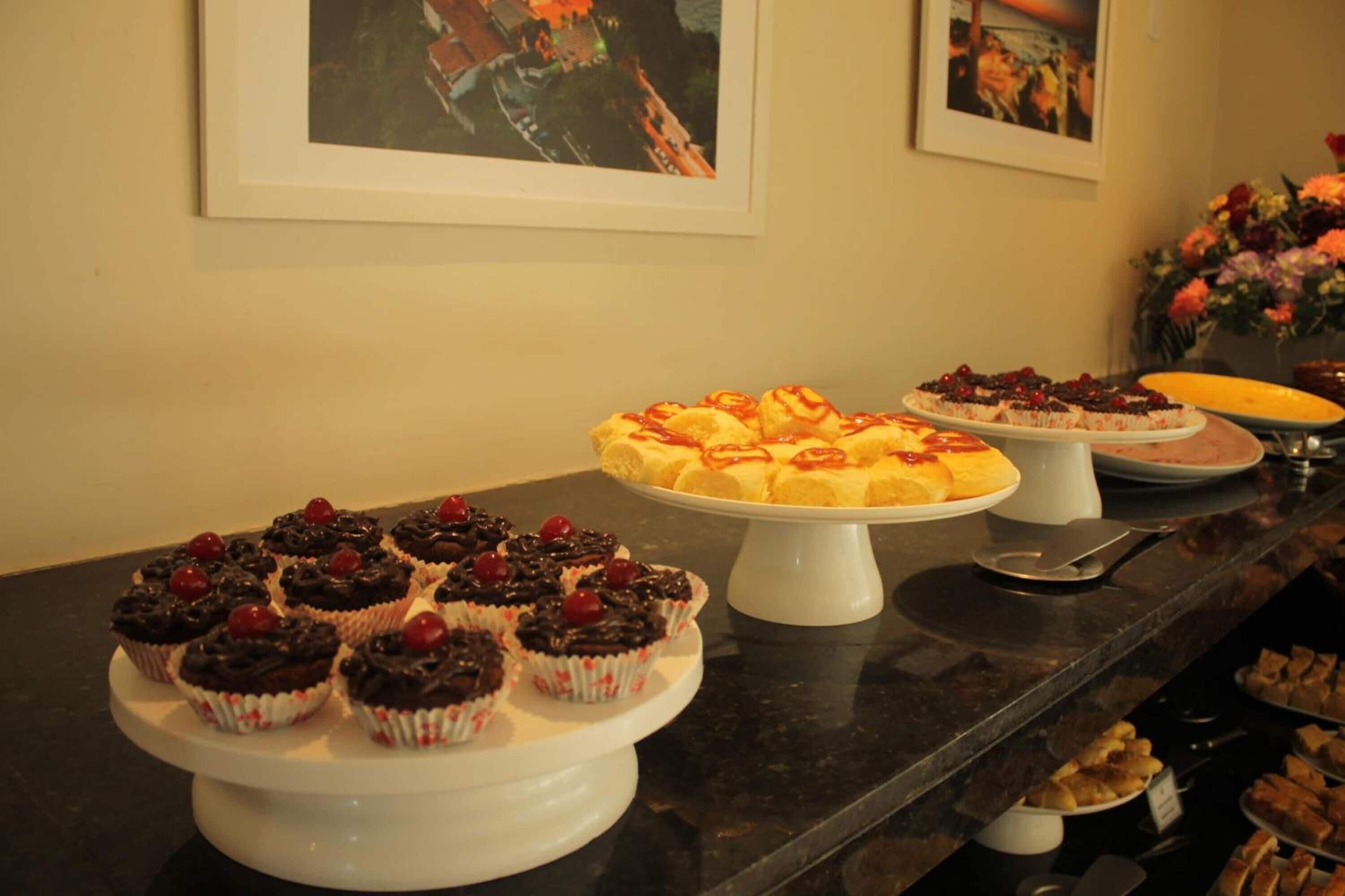 Una mesa de buffet con diversos postres, como cupcakes y pasteles, sobre soportes blancos.