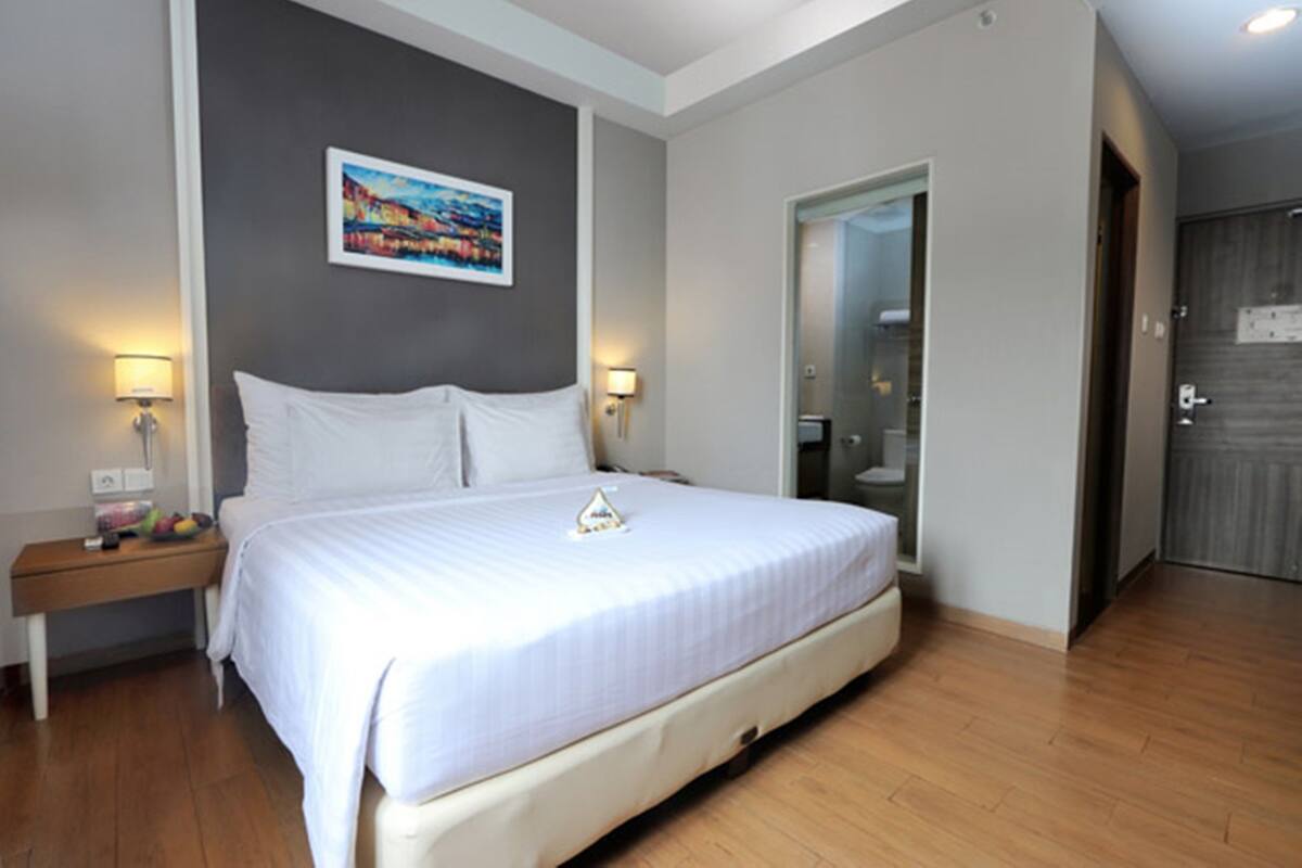 A bedroom with a large bed, bedside lamps, a nightstand, and a painting on the wall.