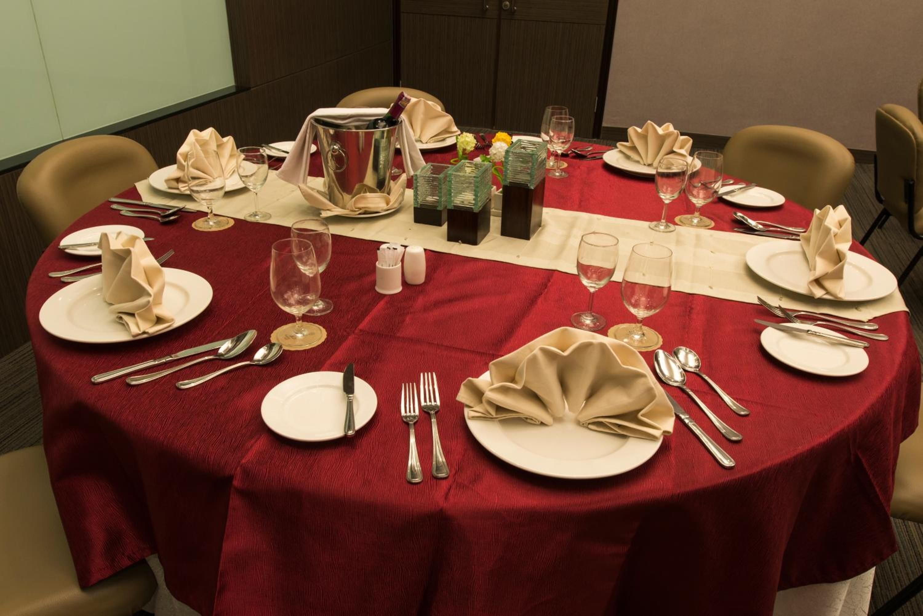 A round table set for a meal with plates, cutlery, glasses, and a pitcher.