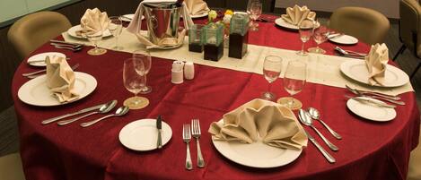 A round table set for a meal with plates, cutlery, glasses, and a pitcher.