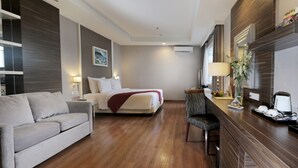 Une chambre d’hôtel comprenant un lit, un canapé, un bureau avec une chaise et un miroir.