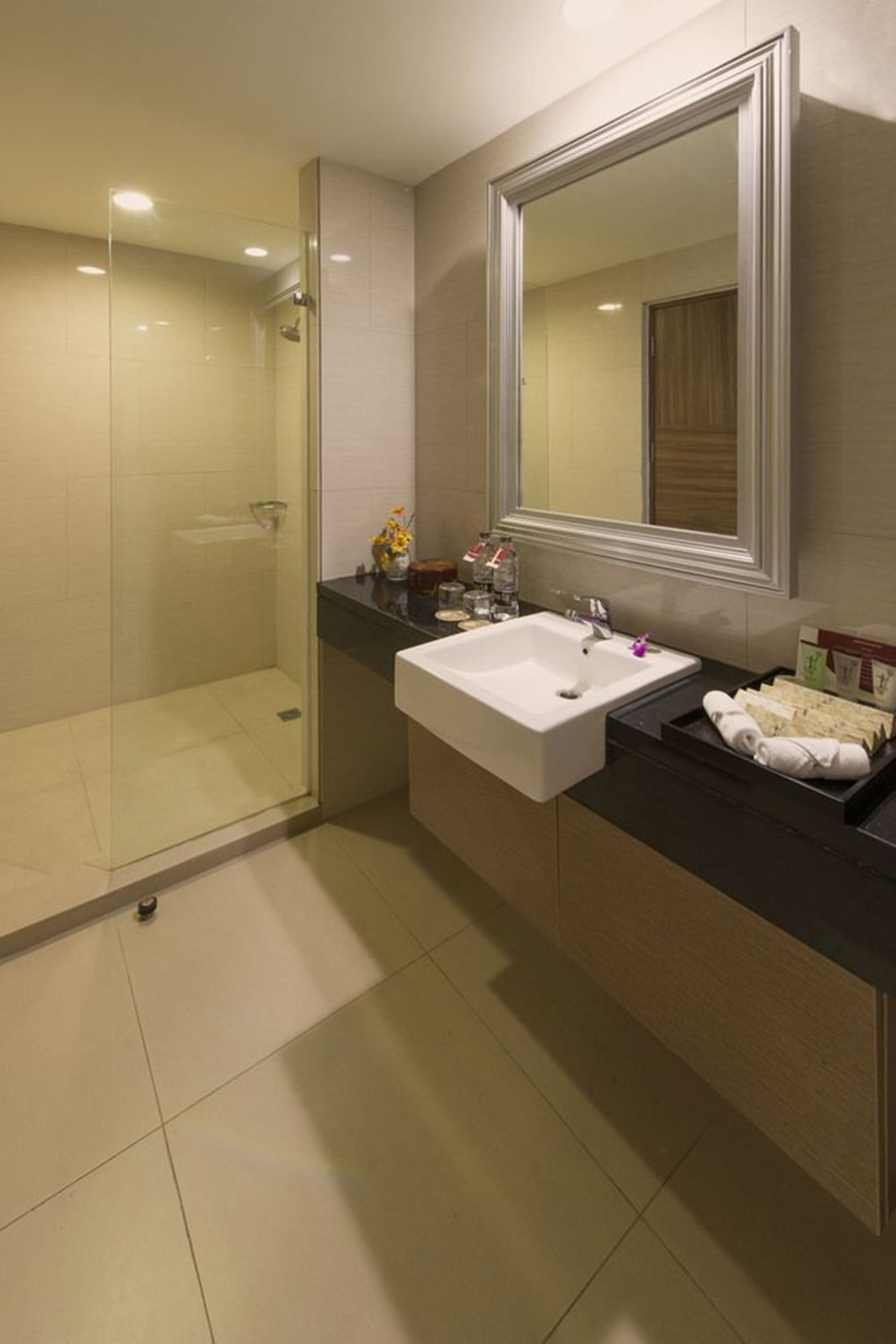 A modern bathroom with a glass-enclosed shower, a white sink, and a large mirror.