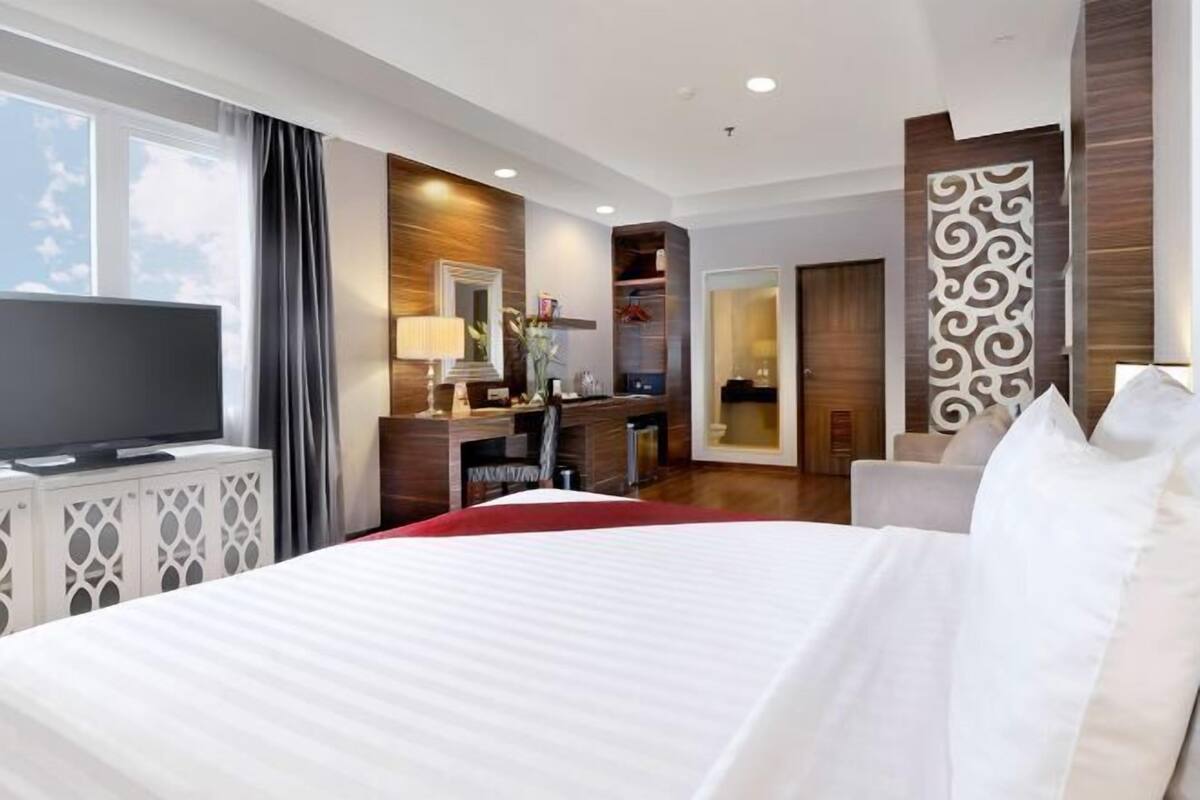 A hotel room with a bed, TV, desk, and wardrobe.