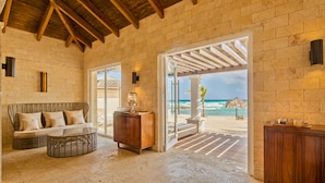 Una habitación junto a la playa con un sofá de mimbre, un armario de madera y una mesa de centro de cristal.