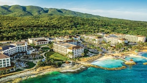 Un complejo turístico con varias edificaciones, una playa y aguas cristalinas.