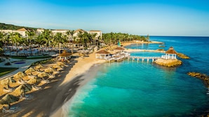 Un resort con playa, agua y edificios.