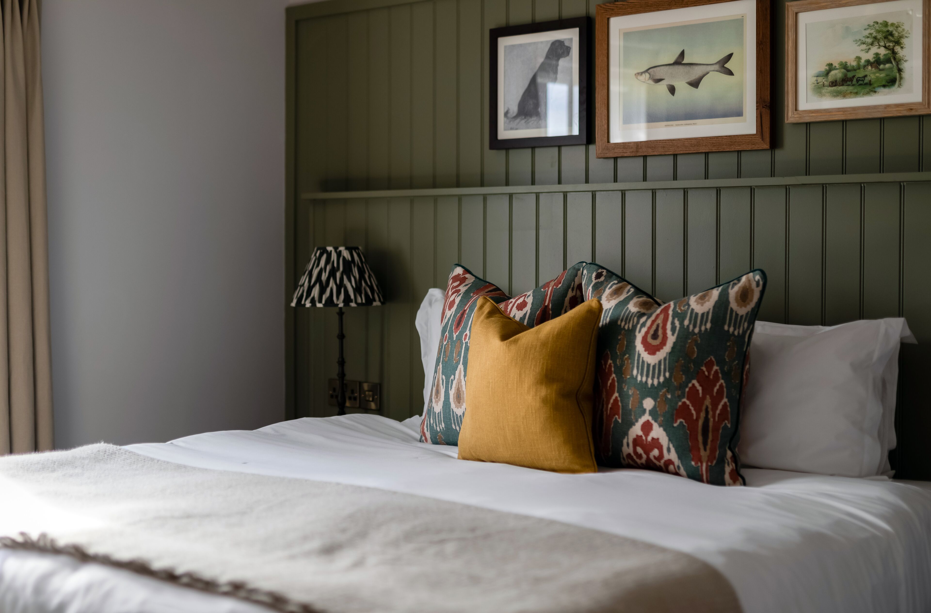 A neatly made bed with patterned pillows and a lamp beside it.