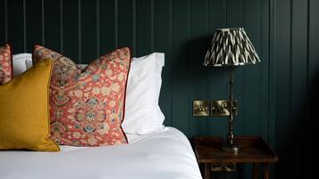 A neatly made bed with patterned pillows, a bedside lamp, and a dark green wall.