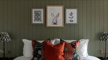 A neatly made bed with patterned pillows, framed artwork on the wall, and two lamps on either side.