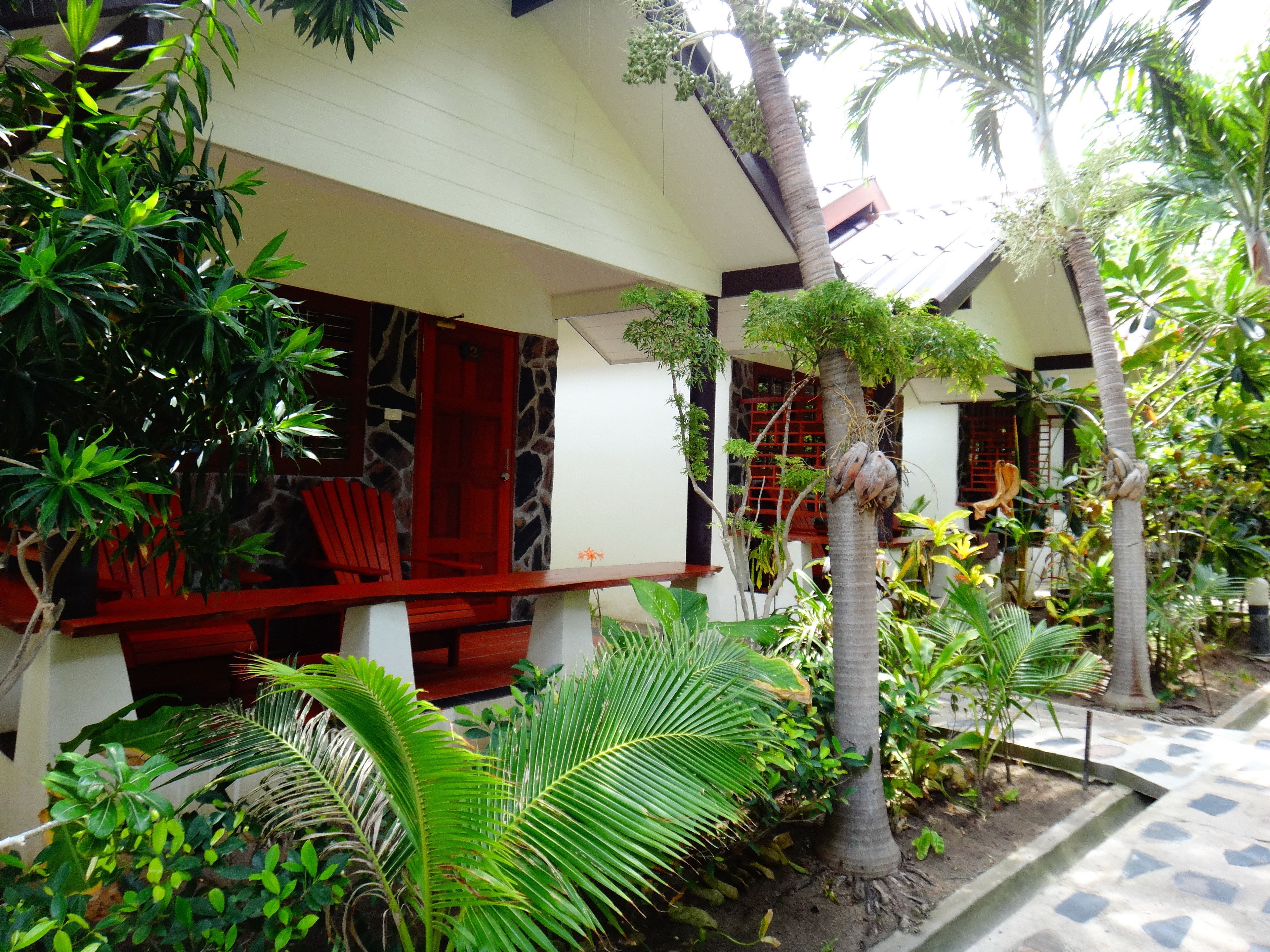 A modern house with a red door, a stone wall, and a small porch with a red chair.