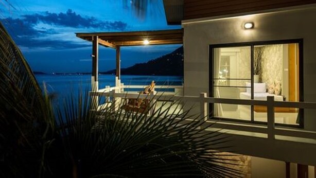 Un edificio moderno con un espacio exterior cubierto, un ventanal grande y vistas al mar.